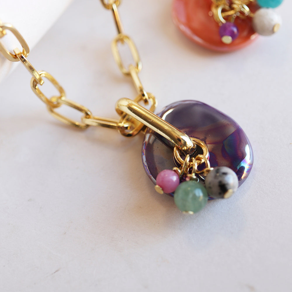 Collar de eslabones dorados con colgante de piedras de colores y diseño moderno.