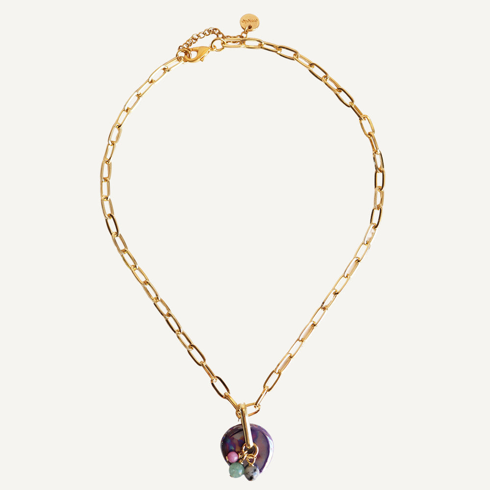 Collar dorado con eslabones grandes y colgante de concha morada y piedras en tonos verdes.