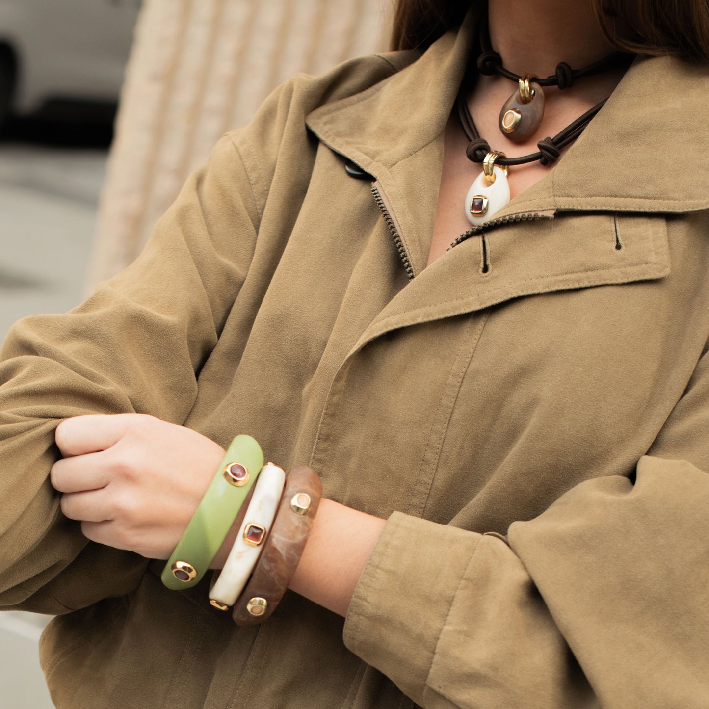 Conjunto de pulseras verdes, marrones y blancas, y collar de cuero con detalles dorados y piedras preciosas.