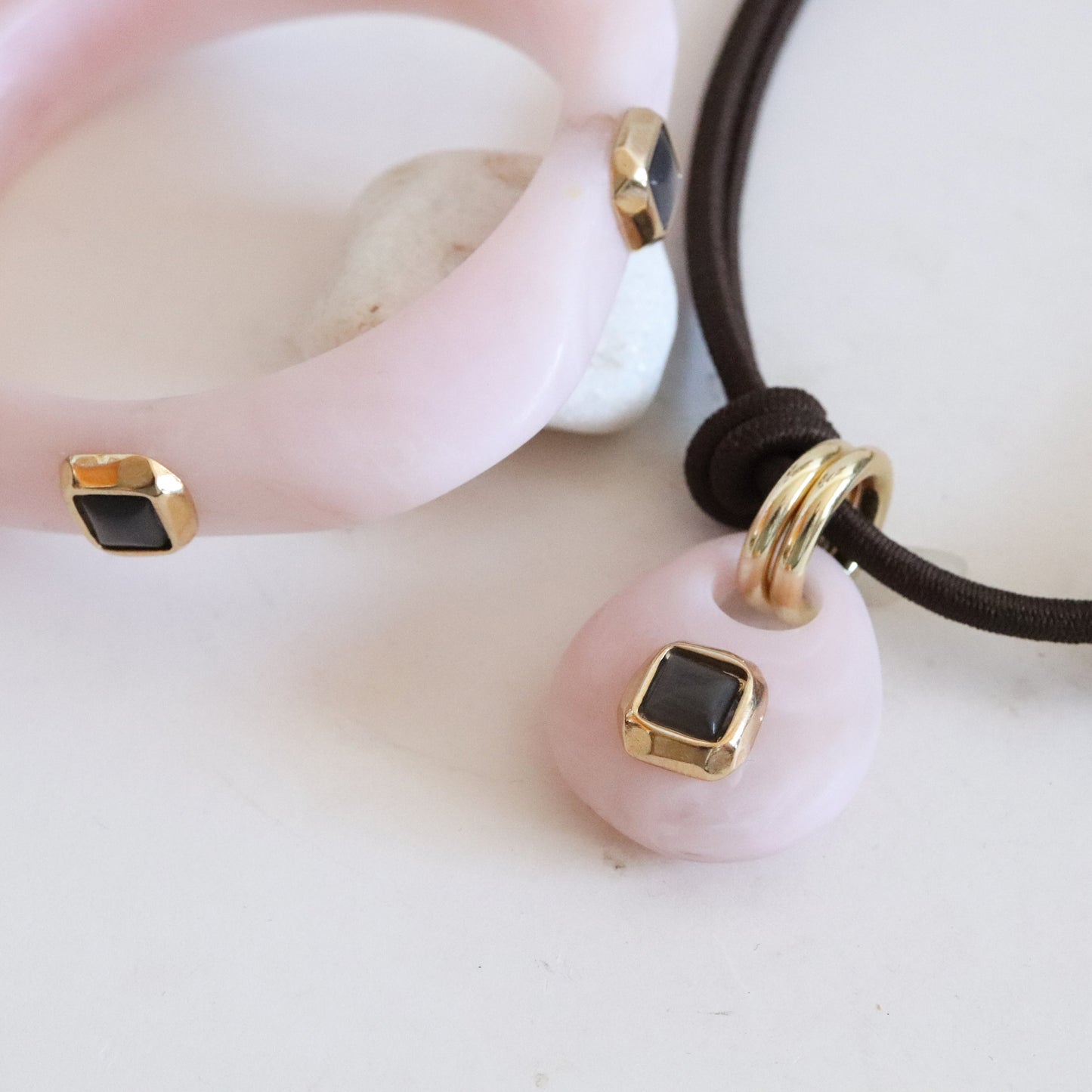 Collar y pulsera de acetato rosa con detalles dorados y negros, estilo moderno y elegante.
