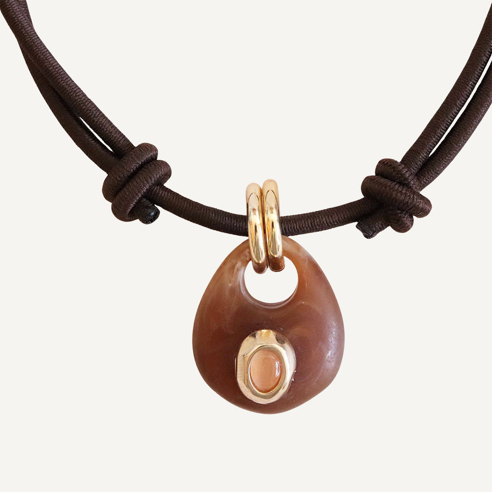 Collar de cuero marrón con colgante de resina marrón y oro, estilo moderno y bohemio.