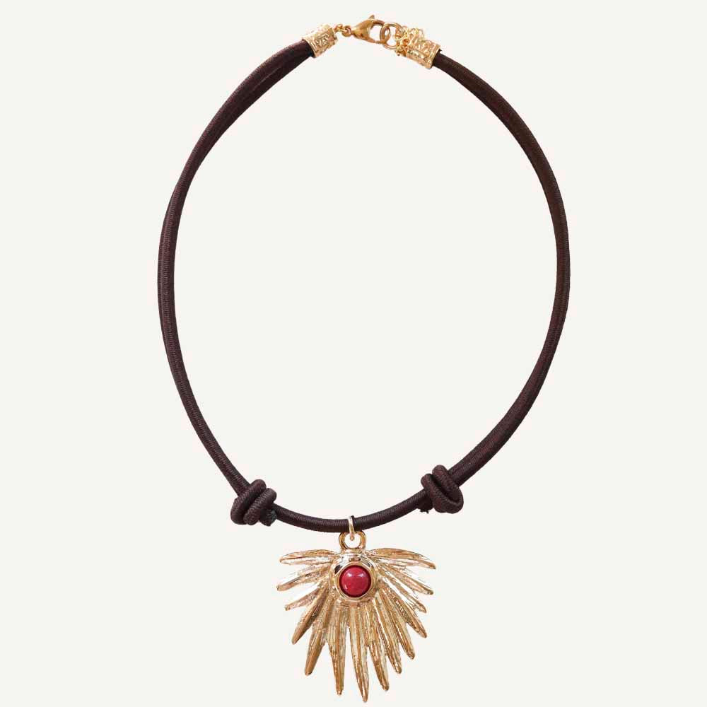 Collar de cuero marrón con colgante dorado en forma de ala y piedra roja, estilo bohemio.