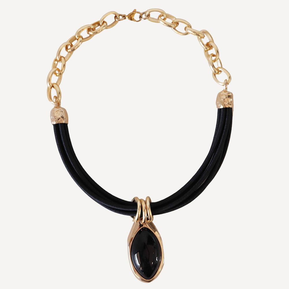 Collar de cadena dorada con detalle de ónice negro y cordón de goma negro, estilo moderno y elegante.