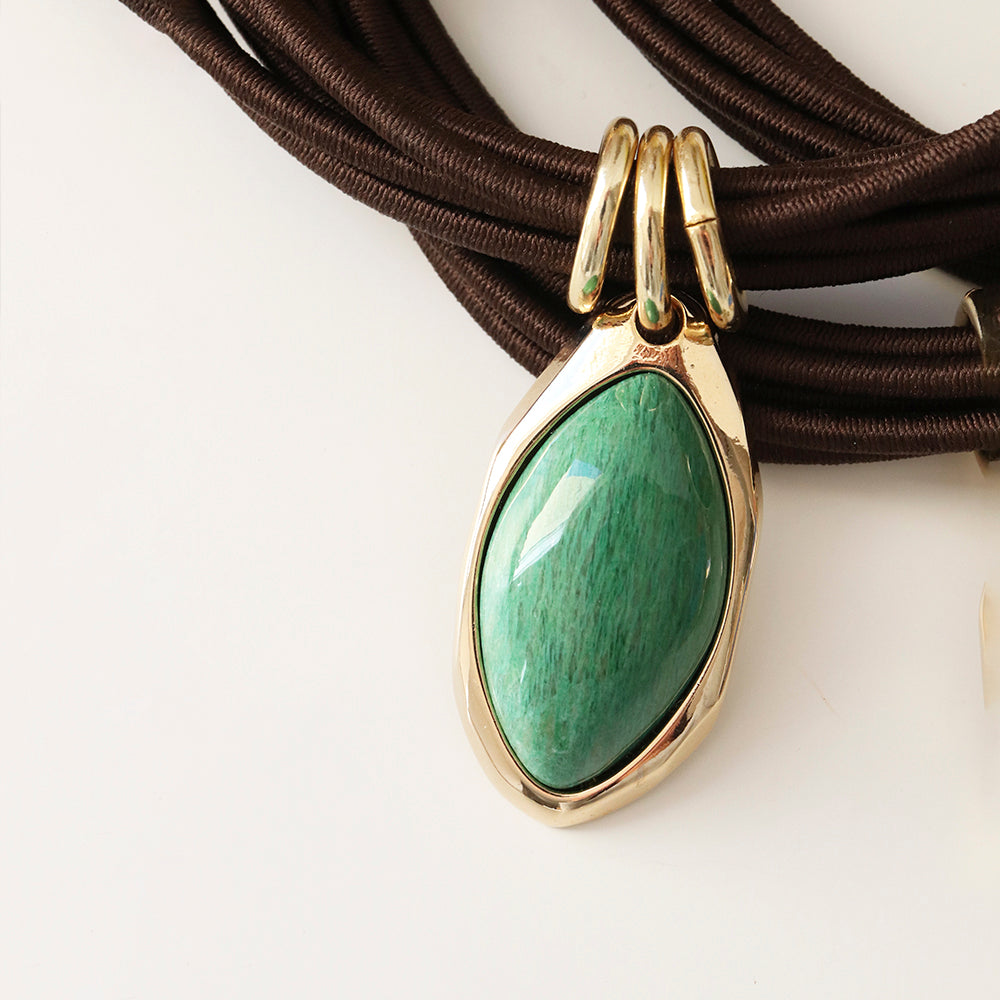 Collar moderno con colgante verde de jade y cadena de cordón marrón, metal dorado, elegante y sofisticado.