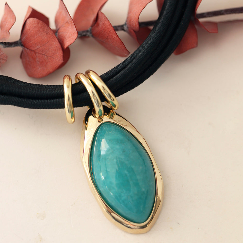 Collar de cerámica negra con colgante de gema verde y detalle dorado, estilo elegante y moderno.