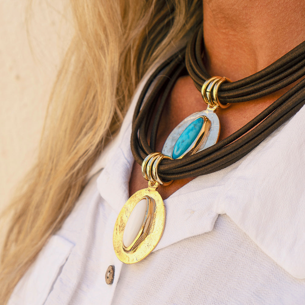 Collar de cuero marrón con colgantes ovalados dorados y piedras azul y blanca, estilo bohemio y elegante.