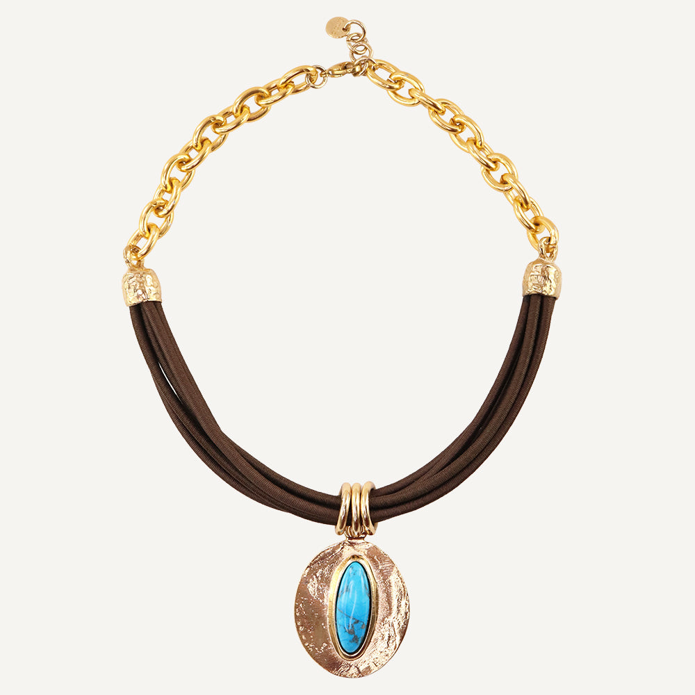 Collar de cadenas doradas con cuero marrón y piedra turquesa central, estilo bohemio y elegante.
