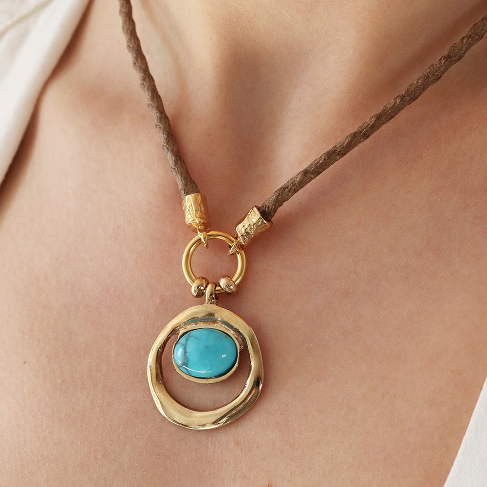 Collar de cuerda marrón con colgante dorado y turquesa, estilo bohemio y elegante.