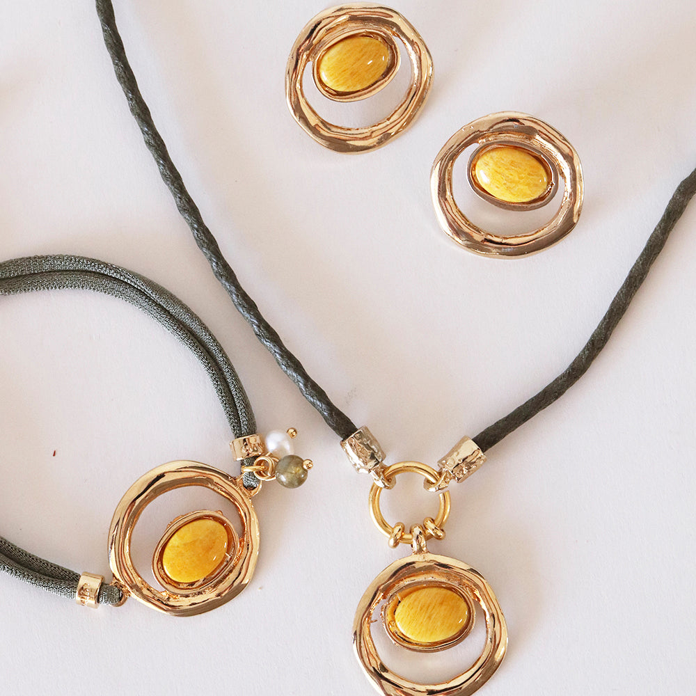 Conjunto de joyas de oro y amarillo, incluye pulsera y aretes, con detalles en cuerda gris y diseño moderno.