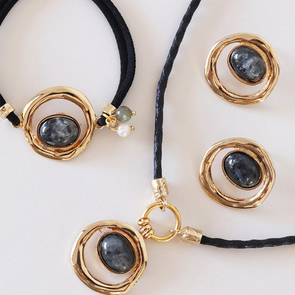 Collar y aretes de oro con piedras negras, detalles en perla, diseño moderno y elegante.