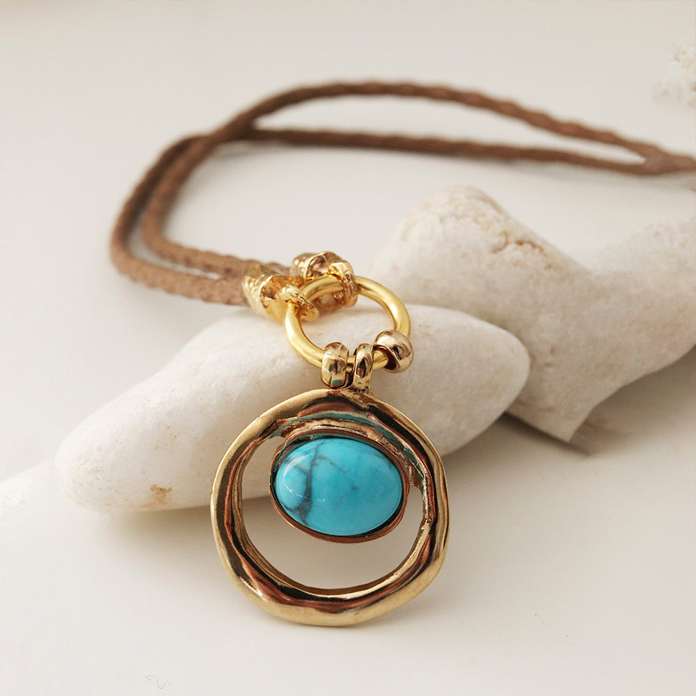 Collar de cuero trenzado con colgante dorado y piedra turquesa en forma ovalada. Elegante y bohemio.