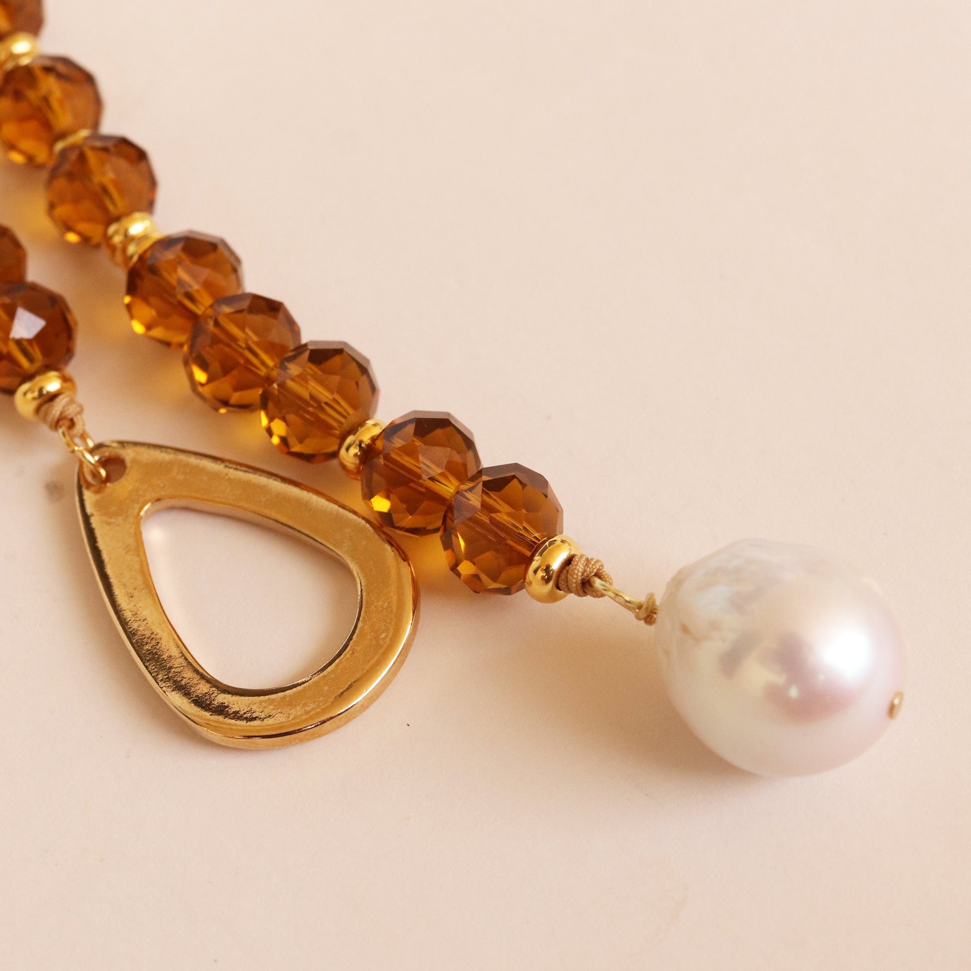 Collar de cuentas ámbar, perla blanca y detalle dorado, estilo elegante y moderno.