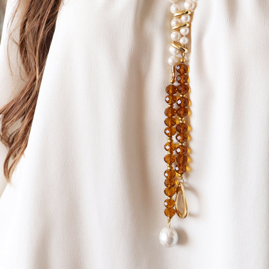 Collar elegante de perlas y cristal ámbar, con detalles dorados y acabado brillante, ideal para ocasiones especiales.