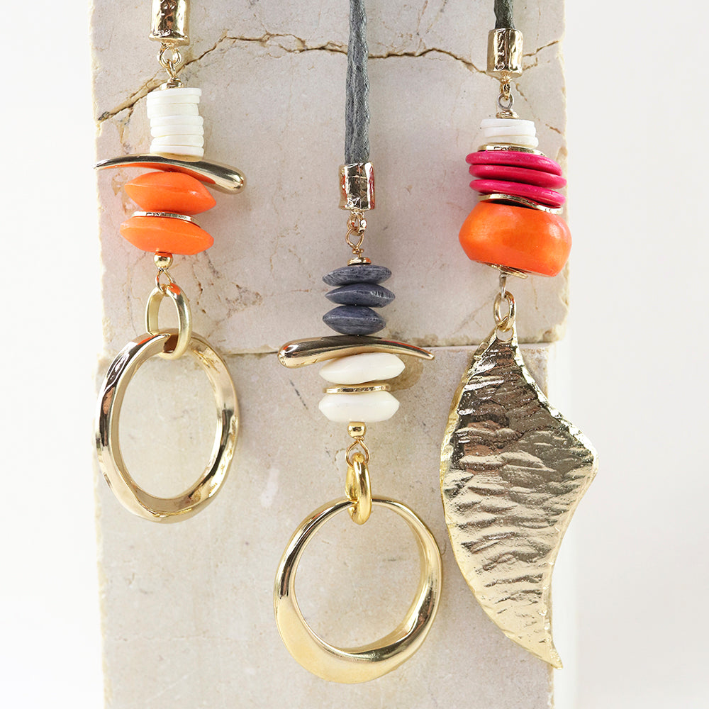 Collar bohemio con pomos de cerámica naranja, rosa y gris, y detalles en metal dorado.