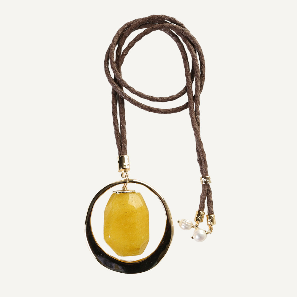 Collar de cuero marrón con colgante amarillo de resina y detalles dorados, incluye perlas blancas.