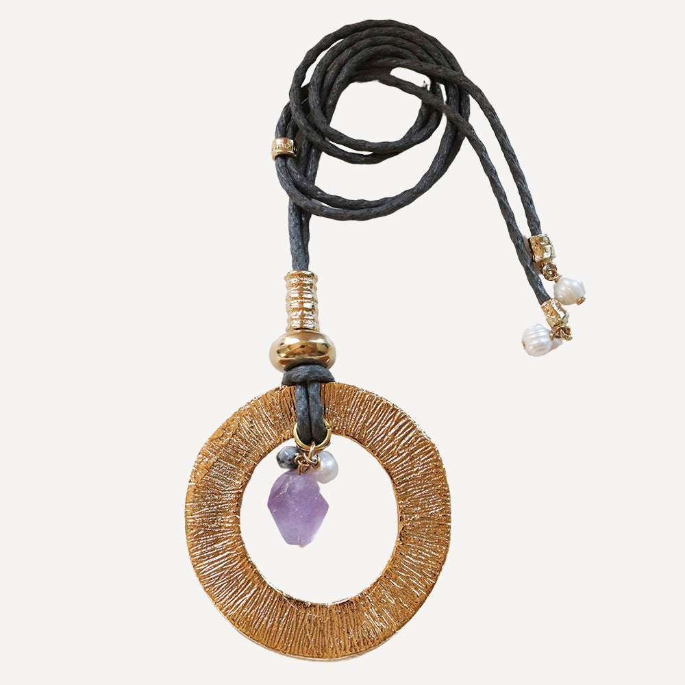 Collar bohemio con colgante dorado, cordón negro y piedra de amatista, estilo elegante y único.
