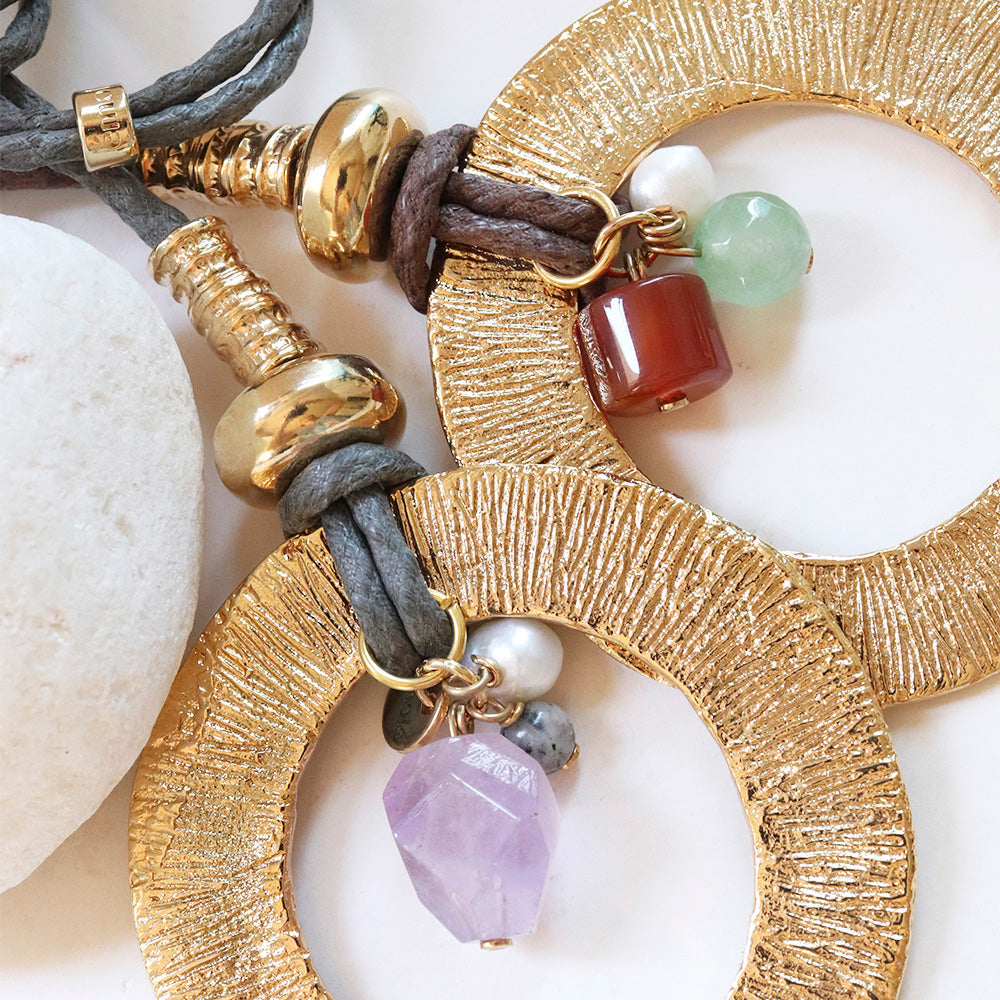 Pendientes grandes dorados con piedras naturales, cordón gris y detalles en perlas, estilo bohemio.