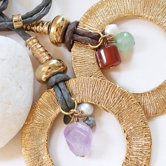 Pendientes grandes dorados con piedras naturales, cordón gris y detalles en perlas, estilo bohemio.