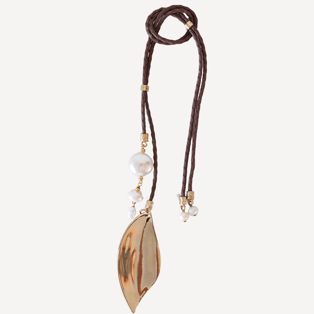 Collar largo de cuero marrón con hoja dorada y perlas blancas, estilo bohemio y elegante.