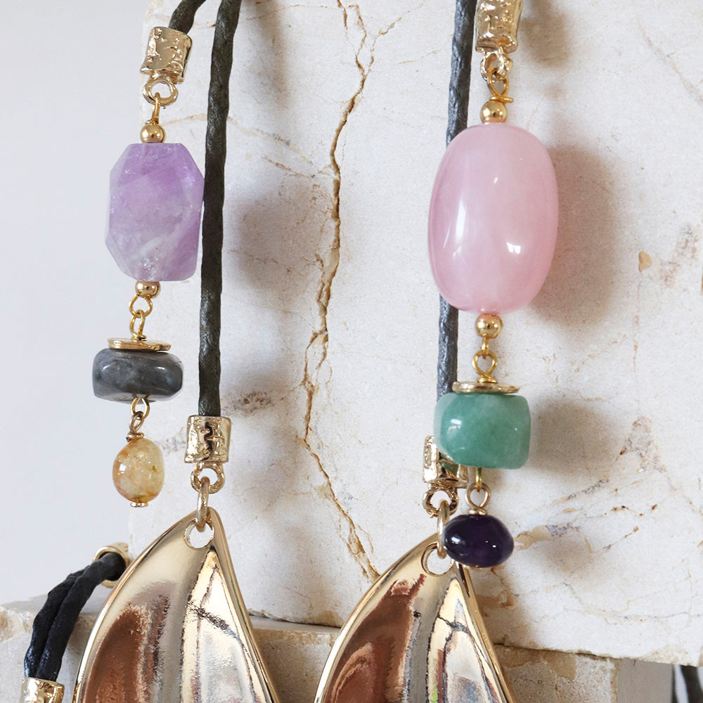 Collar de piedras preciosas en tonos morados, rosa, verde y negro, con detalles dorados. Diseño moderno y elegante.