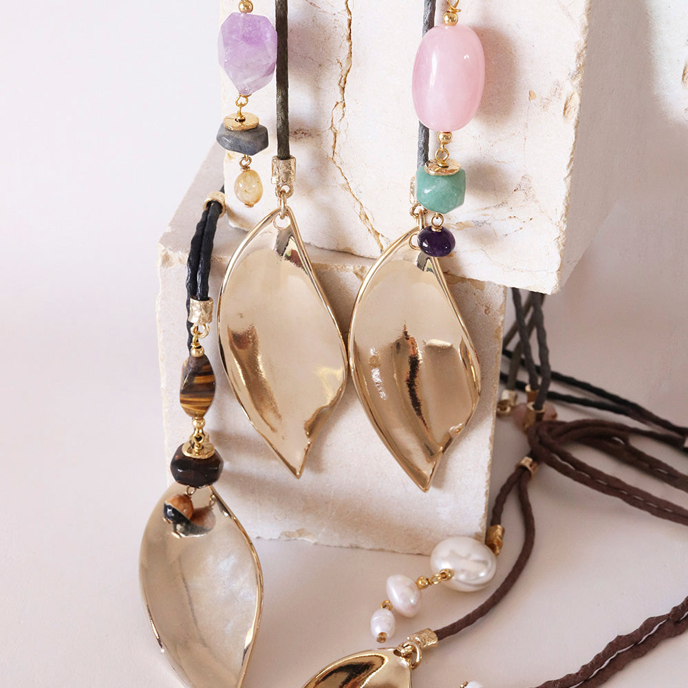 Collares de diseño elegante con cuentas de ágata, cuarzo y perlas, en tonos dorados y naturales sobre soporte blanco.