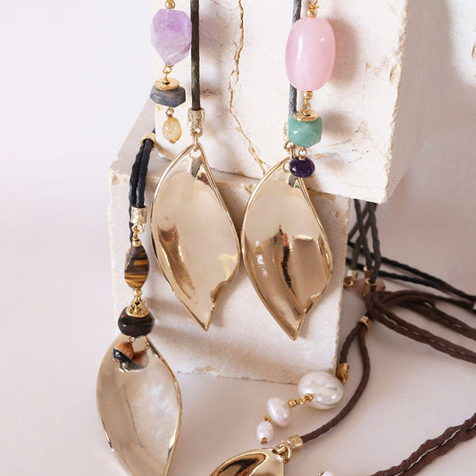 Collares de diseño elegante con cuentas de ágata, cuarzo y perlas, en tonos dorados y naturales sobre soporte blanco.