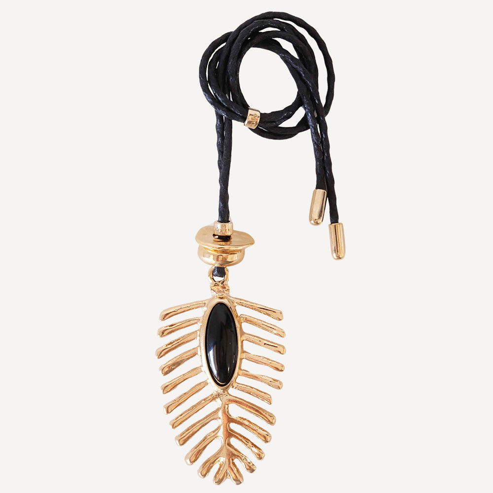 Collar de metal dorado con diseño de hoja y piedra negra, sujeto por cordón de cuero negro.