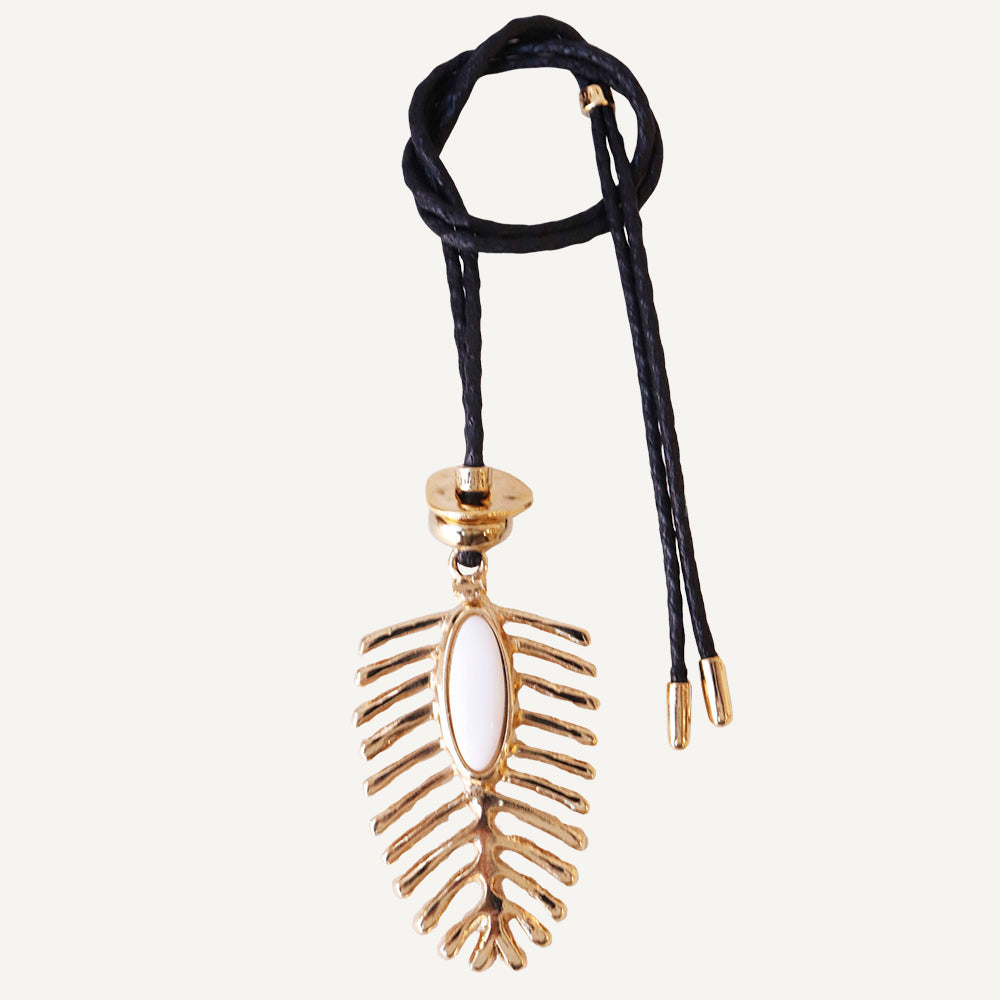Collar bohemio de metal dorado con diseño de hoja y cordón negro, cuenta blanca en el centro.