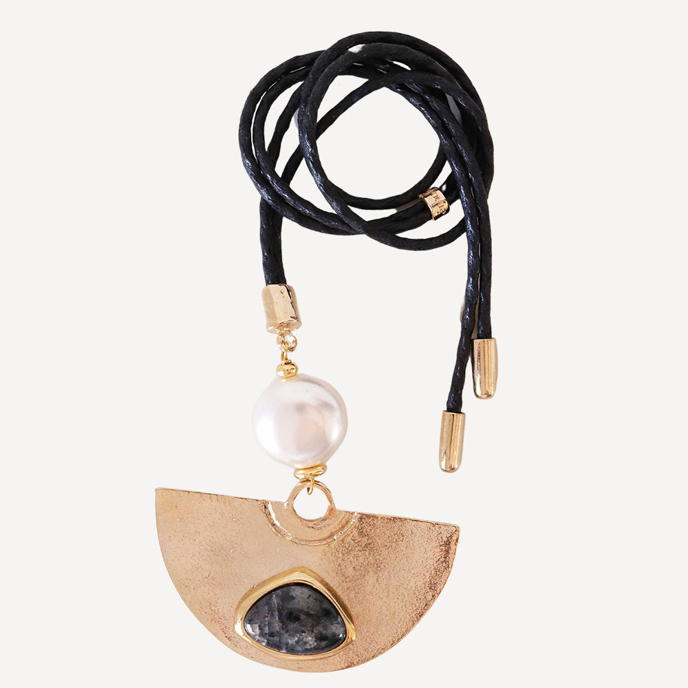 Collar de cordón negro con colgante dorado, piedra negra y perla blanca, estilo moderno y elegante.