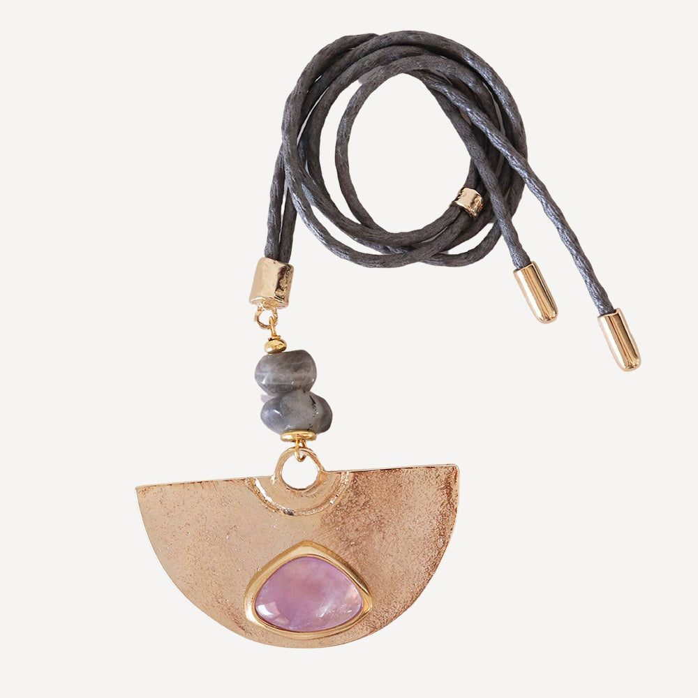 Collar de cuero gris con colgante dorado y piedra violetas, estilo bohemio y moderno.