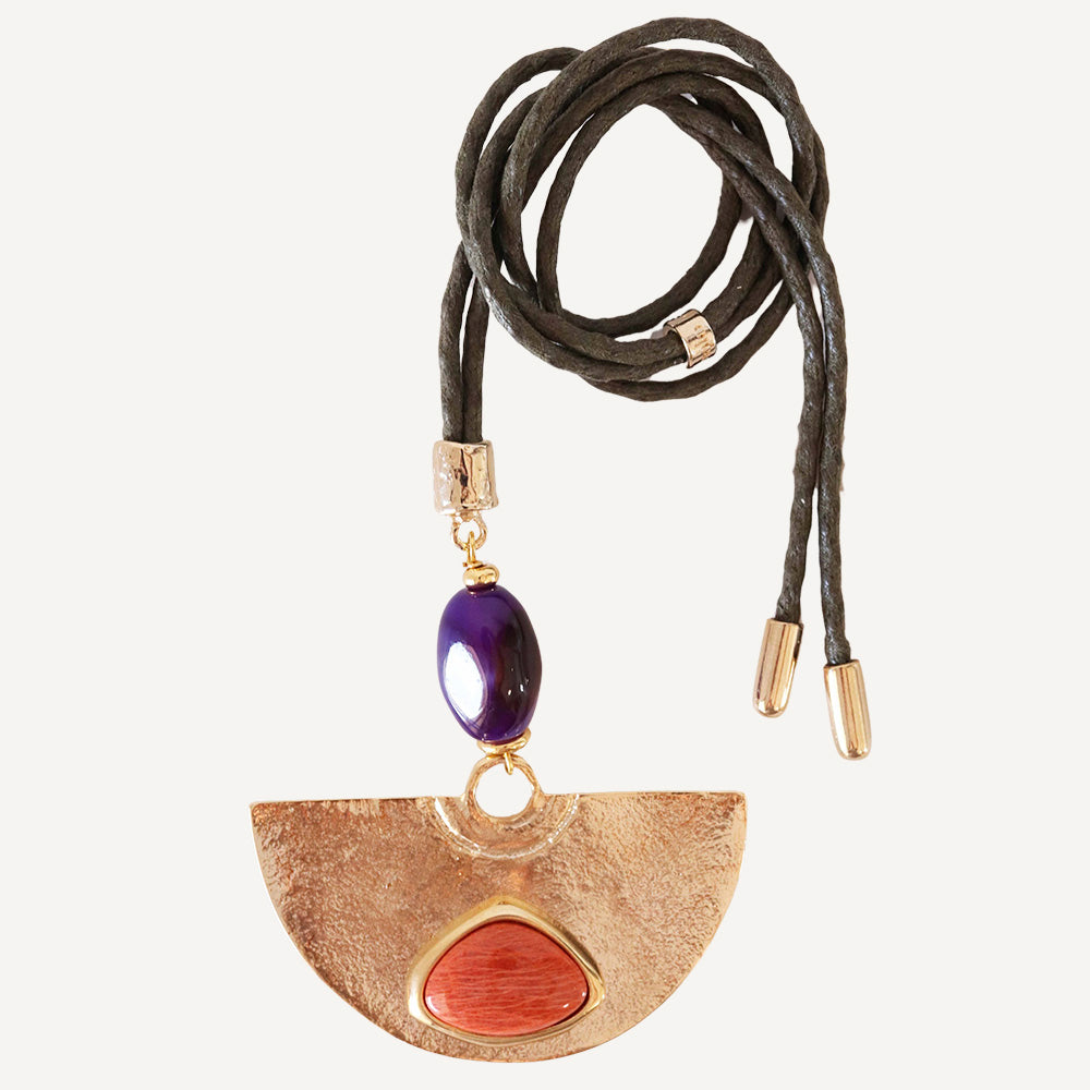 Collar de cuero negro con colgante dorado y piedras naturales en tonos morado y rojo. Estilo bohemio y elegante.