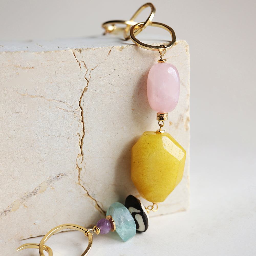 Pendientes largos en oro con piedras amarillas, rosas y verdes, estilo bohemio y moderno.