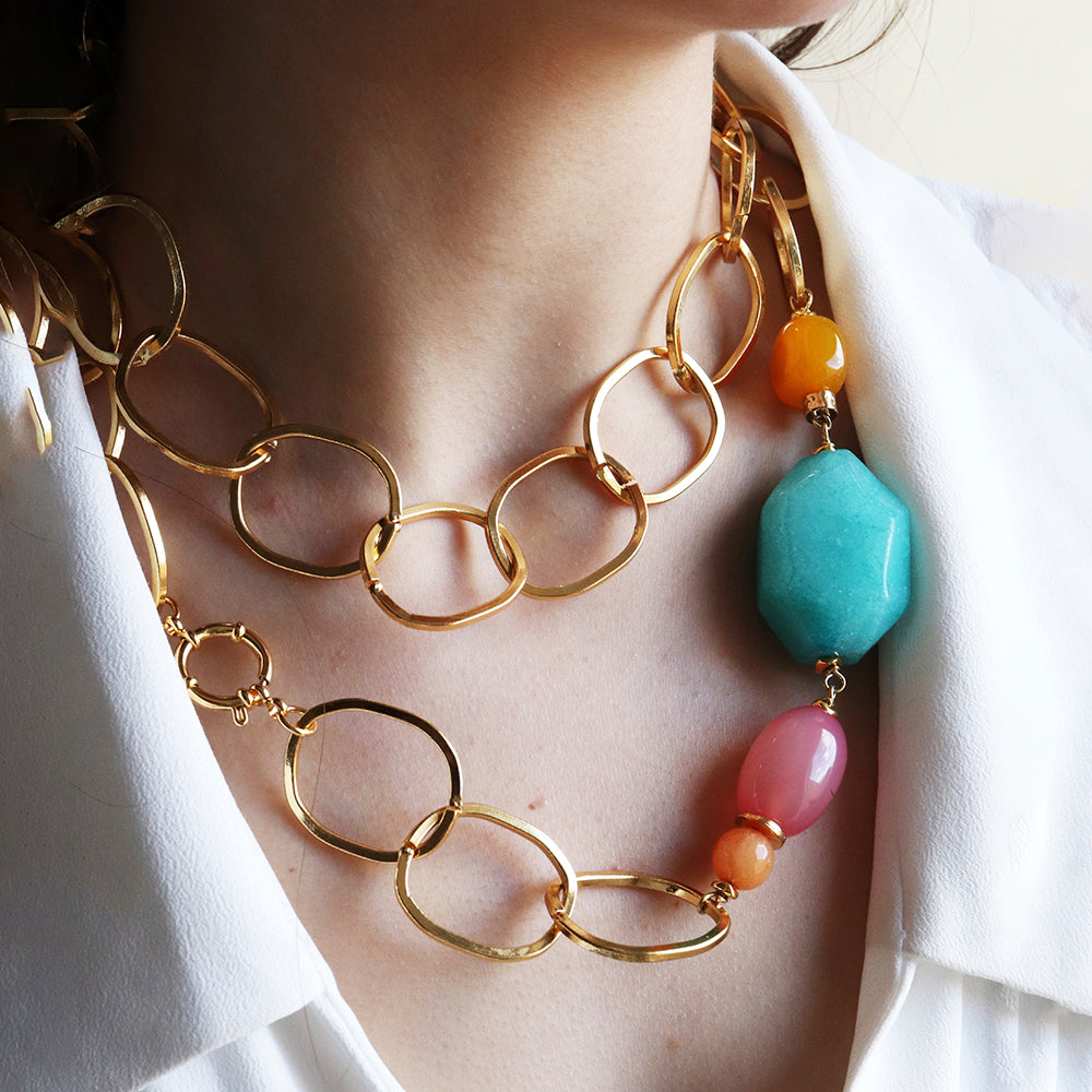 Collar de eslabones dorados con piedras coloridas: turquesa, fucsia y naranja, estilo moderno y vibrante.