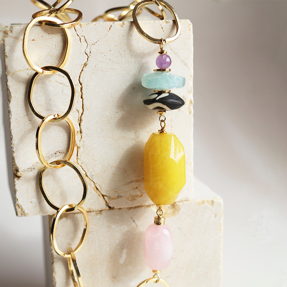 Collar de eslabones dorados con cuentas de ónix, amatista, aguamarina y piedra amarilla. Estilo elegante y moderno.