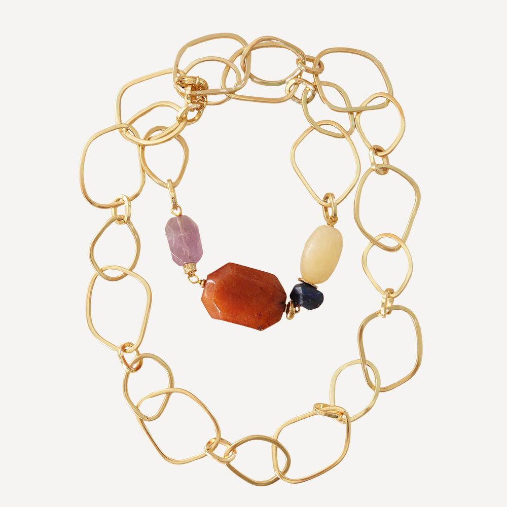 Collar dorado de eslabones con piedras preciosas en tonos naranja, púrpura y amarillo. Estilo elegante y moderno.