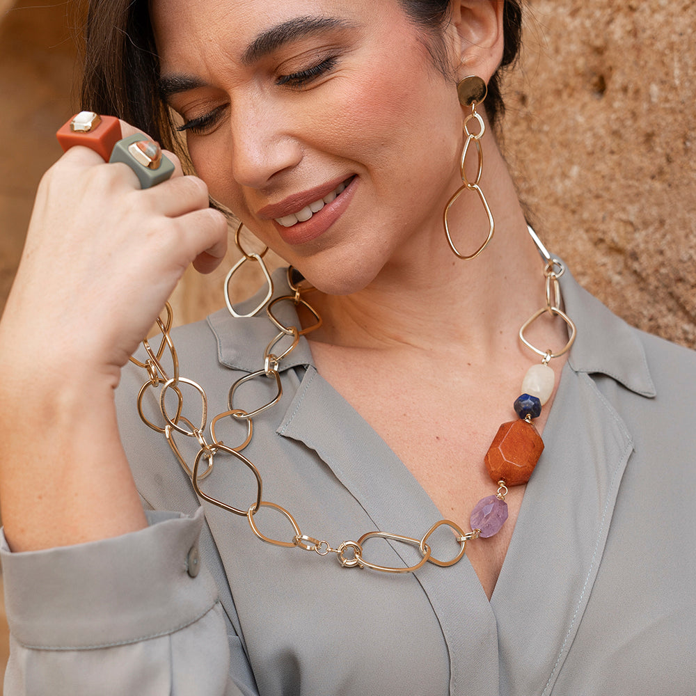 Collar largo de eslabones dorados con cuentas de piedras naturales en tonos naranja, verde y púrpura. Elegante y moderno.