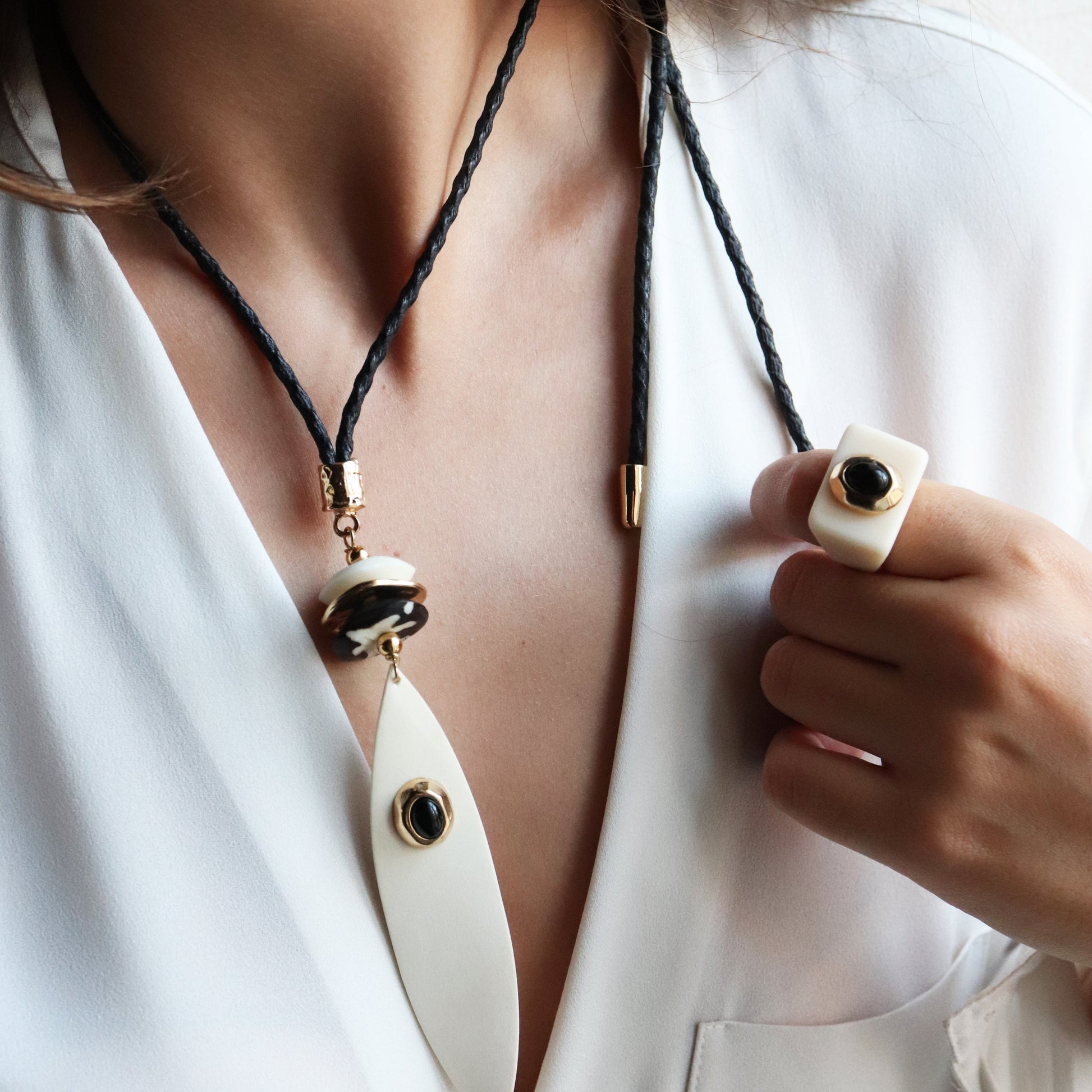 Collar de hilo negro con adornos blancos y negros, elegante y moderno, ideal para ocasiones especiales.