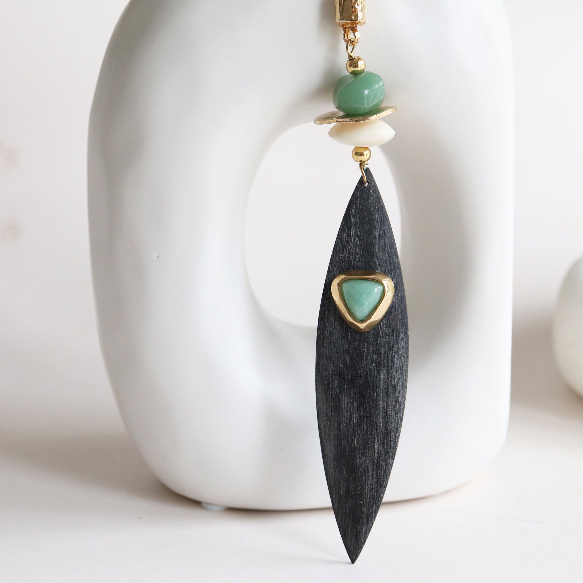 Pendientes de madera negra con detalle dorado y cuentas verdes, estilo moderno y elegante.