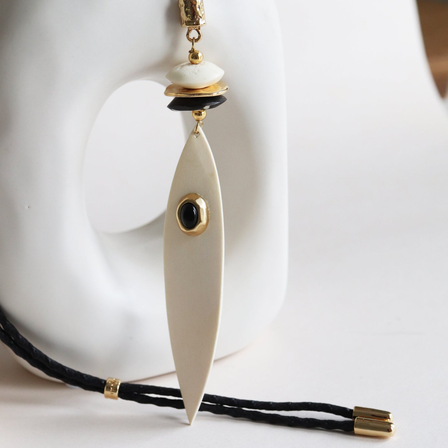 Collar largo de resina en tonos blancos y negros con detalles dorados y diseño elegante.