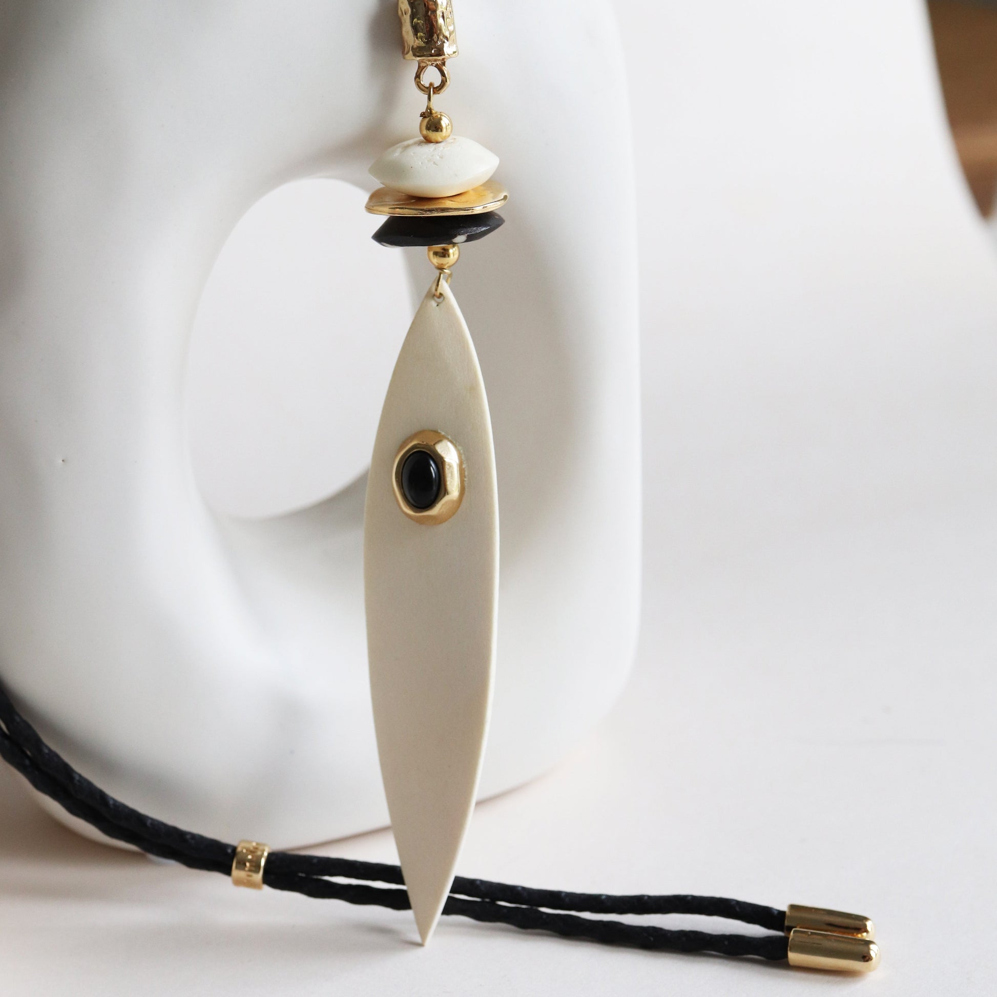 Collar largo de resina en tonos blancos y negros con detalles dorados y diseño elegante.