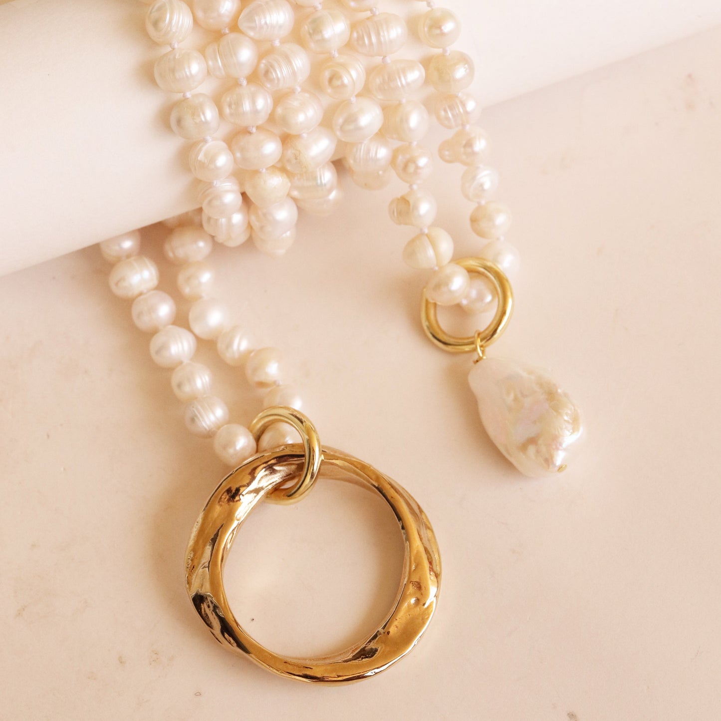 Collar de perlas blancas con anillo dorado y colgante de perla única, estilo elegante y moderno.