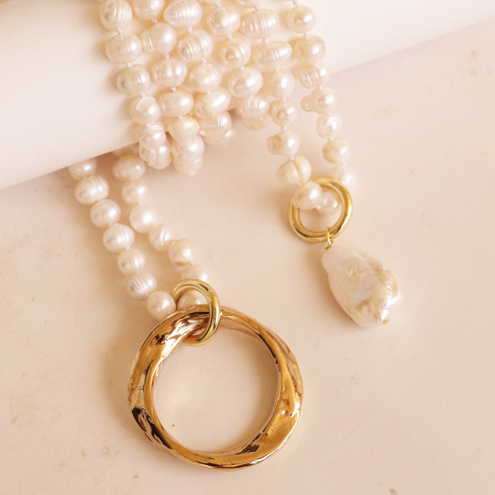 Collar de perlas blancas con anillo dorado y colgante de perla única, estilo elegante y moderno.