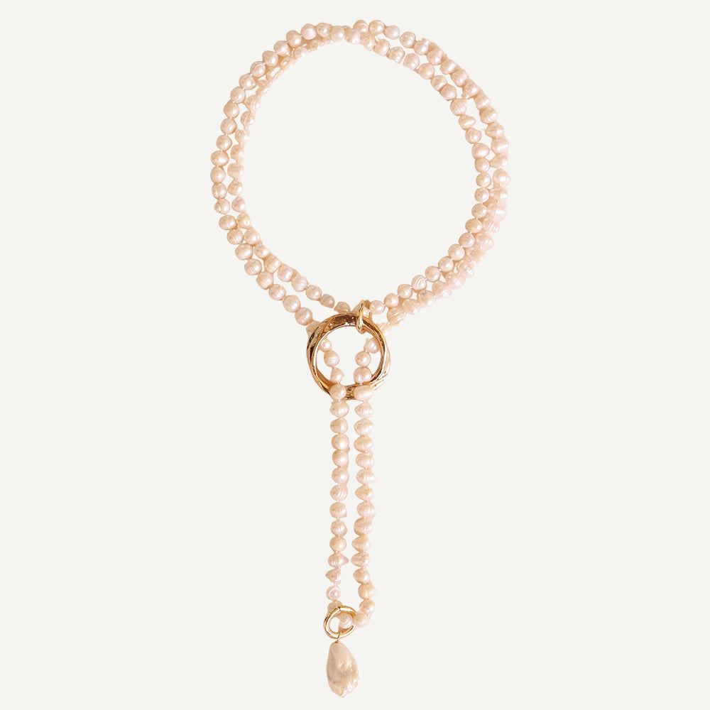 Collar de perlas naturales en tonos crema con detalles dorados y colgante, estilo elegante y moderno.