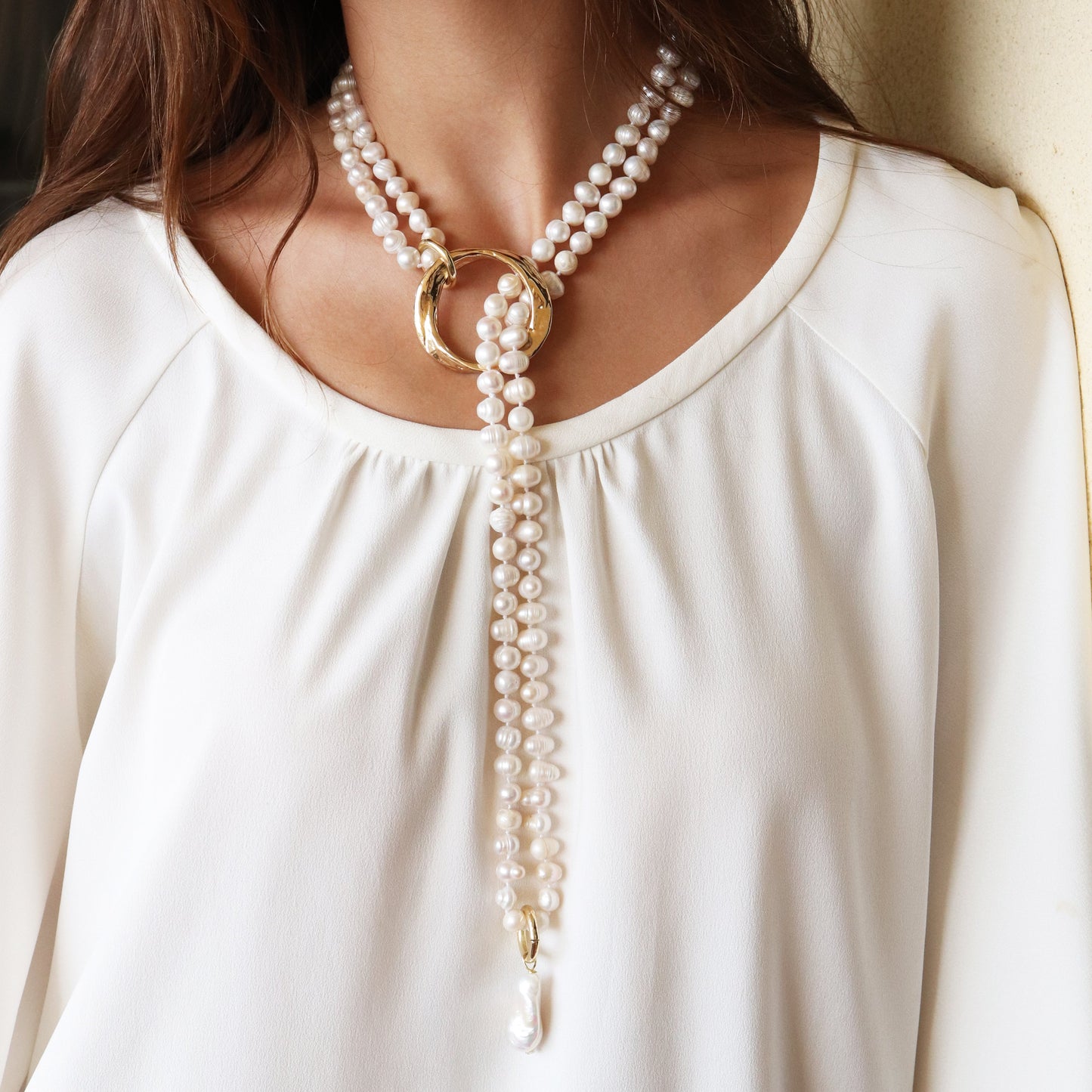 Collar de perlas blancas con aros dorados y detalle en perla, estilo elegante y contemporáneo.