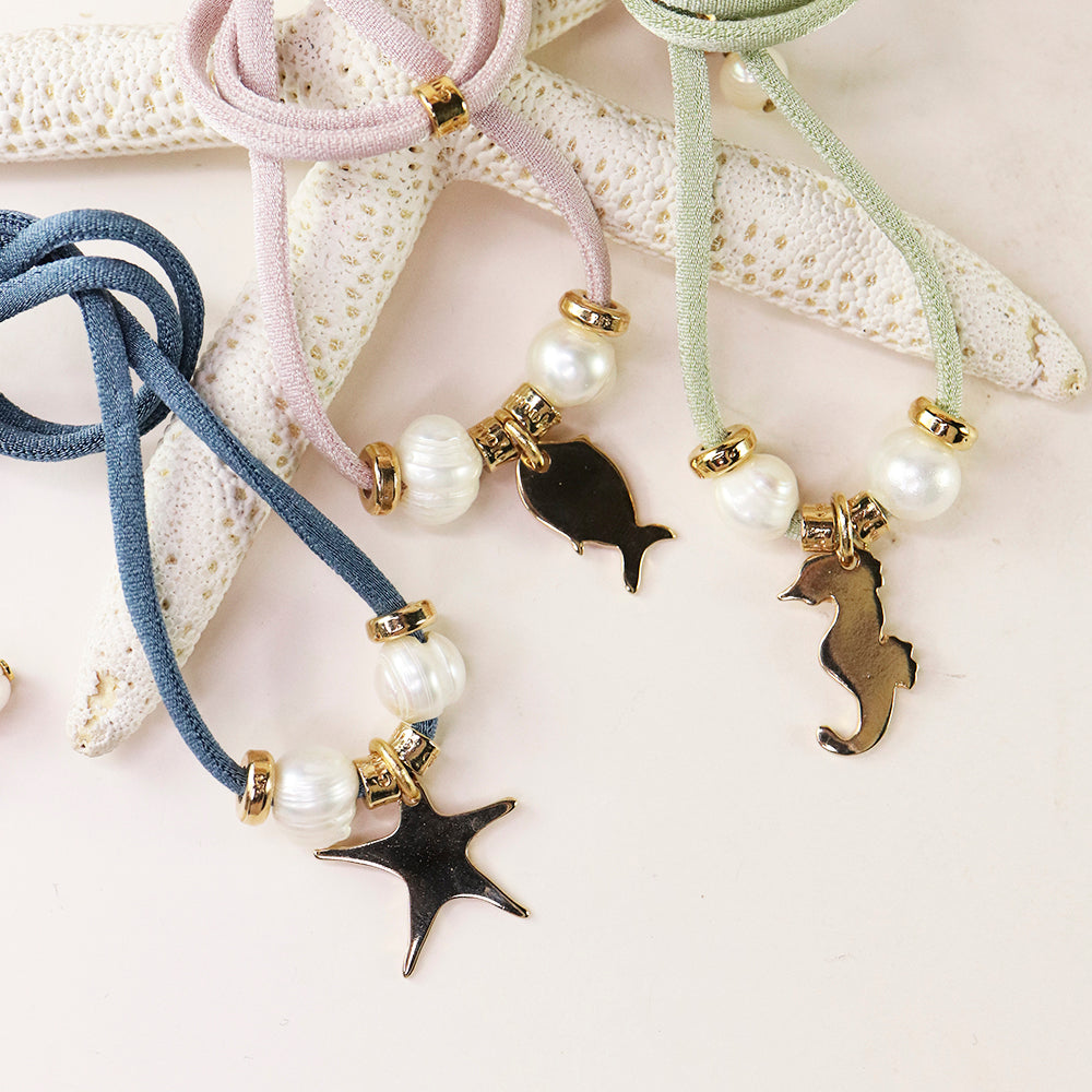 Collares de cordón suave en rosa, azul y verde con dijes de estrella y caballito de mar, perlas y detalles dorados.
