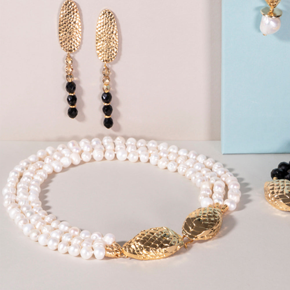 Collar de perlas blancas con detalles dorados y pendientes largos de oro, elegante y sofisticado.