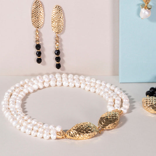 Collar de perlas blancas con detalles dorados y pendientes largos de oro, elegante y sofisticado.