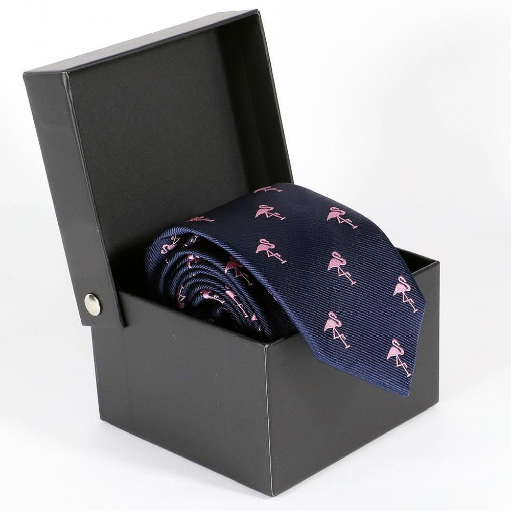 Corbata azul marino con flamencos rosas presentada enrollada en caja de regalo negra abierta