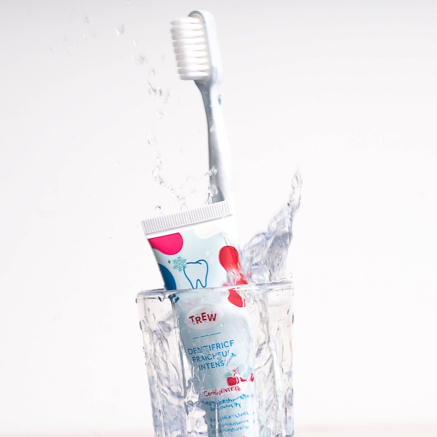 Tube de dentifrice Trew Cerise Givrée et brosse à dents dans un verre d'eau avec éclaboussures sur fond blanc.