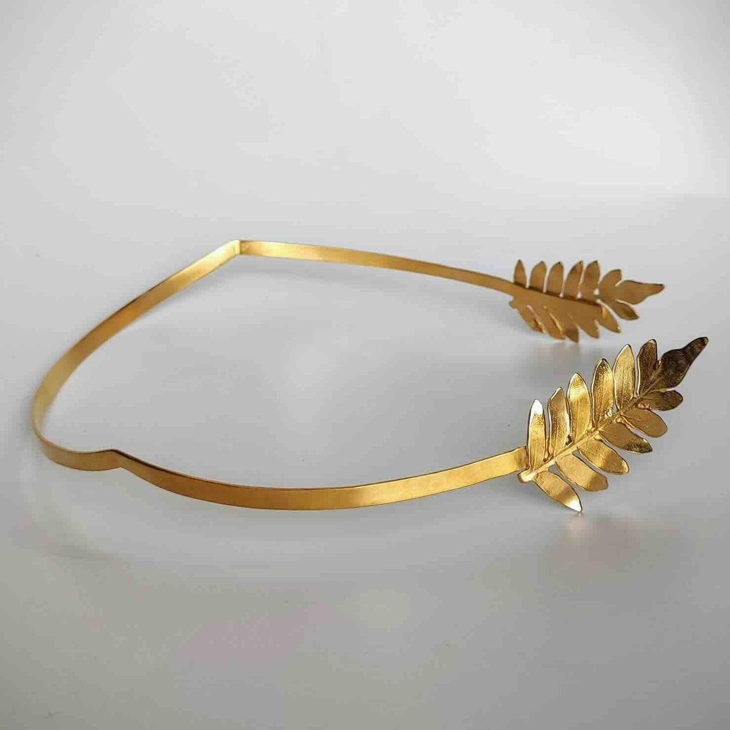 Diadema dorada de metal con diseño de hojas, elegante y contemporánea para un look sofisticado.